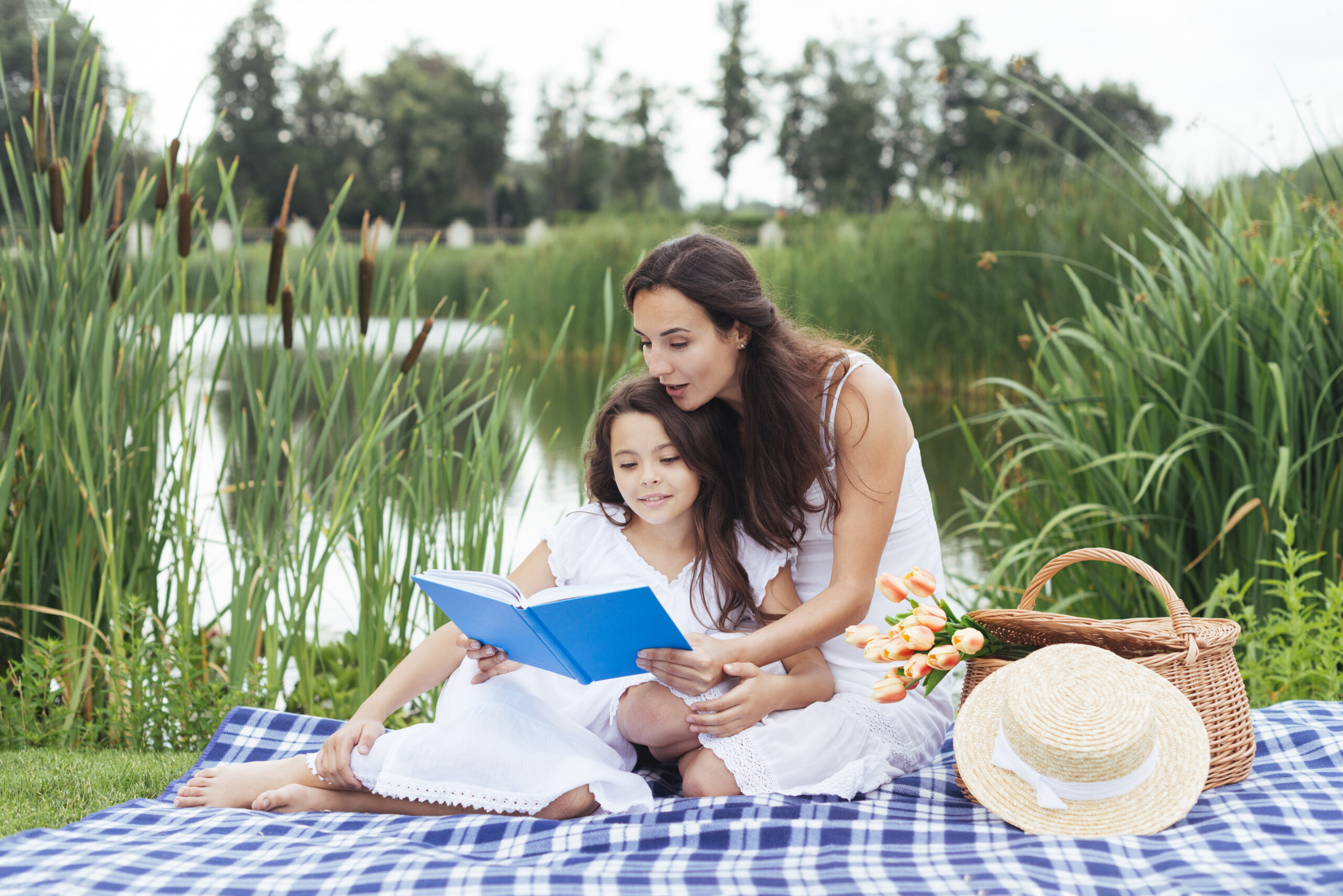 mother daughter reading book by lake